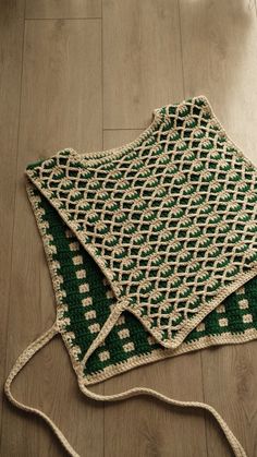 a crocheted green and white blanket laying on the floor