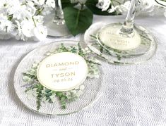 two personalized wine glasses sitting on top of a table with flowers in the background