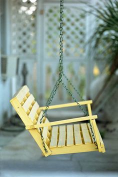 a yellow swing chair hanging from a chain