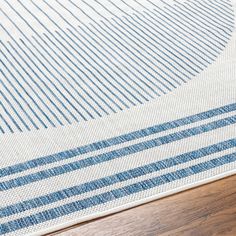 a blue and white striped rug on a wooden floor with a wood floor in the background