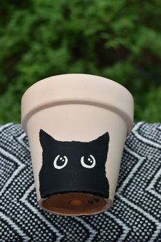 a black cat face painted on a flower pot