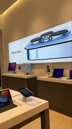 an apple store with several different laptops on the tables and in front of a big screen