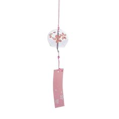 a pink and white wind chime hanging from a string with flowers on it's side