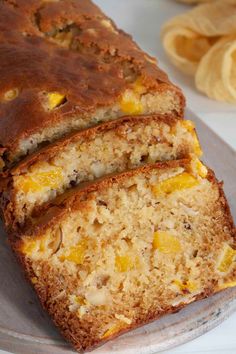 two slices of fruit bread on a plate next to some sliced bananas and oranges