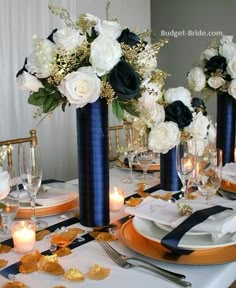 the table is set with black and white flowers in tall vases, gold place settings, and candles