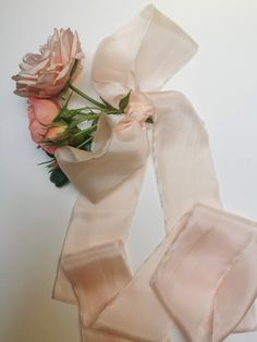 two pink roses are sitting on top of a white scarf