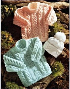 three knitted sweaters and hats sitting on the ground