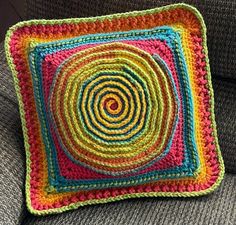 a crocheted square on a couch with the center made out of multicolored yarn