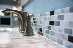 the faucet is next to the sink in the bathroom with blue and white tiles