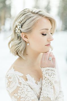 a woman wearing a white dress standing in the snow with her hand on her chin