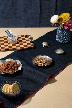 a table topped with plates of food next to a vase filled with wildflowers