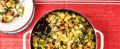 a casserole dish with broccoli and other vegetables on a red tablecloth