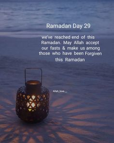 a lantern sitting on top of a sandy beach next to the ocean with a quote from ramadan day 29