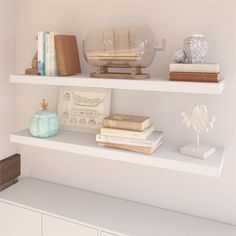 some books and other items are sitting on the shelves in this white room with neutral colors