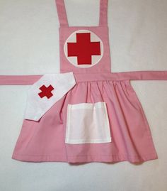 a child's pink dress with red cross on the front and white patchwork on the back