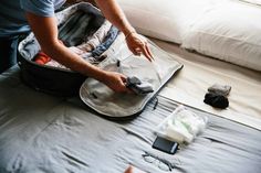 the man is packing his luggage on the bed