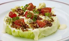 lettuce topped with tomatoes and other toppings on a white plate