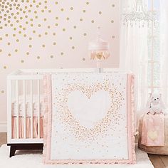 a white crib with a pink and gold bedding next to a teddy bear