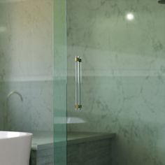 a glass shower door in a bathroom next to a bathtub and sink with a faucet