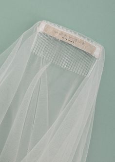 a close up of a white veil with a comb on the top and one piece of fabric attached to it