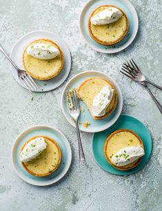 three small pies with whipped cream on them and one has a fork next to it