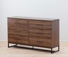 a wooden dresser sitting on top of a hard wood floor next to a white wall