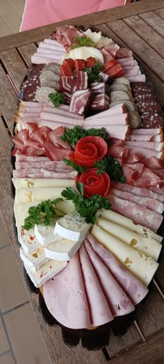 an assortment of meats and cheeses are arranged on a platter with tomatoes