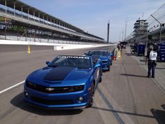 two blue camaros are lined up on the track