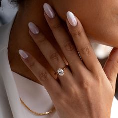 a close up of a woman's hand with a diamond ring on her finger