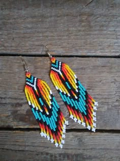 two pairs of colorful beaded earrings sitting on top of a wooden table