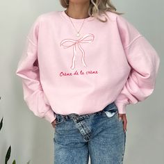 Crème de la crème pink bow crewneck sweatshirt  Sweatshirt Info: ::fabric is 3-end garment-dyed, ring-spun, color-blast fleece with a 100% cotton face.  ::80% ring-spun cotton, 20% polyester ::Medium-heavy fabric  ::Relaxed fit ::Sewn in twill label ::OEKO-TEX certified low-impact dyes FAQs: -Please allow 7 business days for the garment to arrive as it's made to order.  -We do not accept returns due to each shirt being made to order however, if there is an issue please reach out - we're happy to help.  Washing Instructions:  -Please wash garment inside out in cold water with like colors, this protects the integrity of the shirt so it's enjoyed for years to come.  Goldfinch Clothing Co was birthed out of the desire to empower women to step into exactly who they are, unapologetically. Meldin Pink Crew Sweatshirt For Spring, Pink Crew Neck Sweatshirt For Spring, Cute Pink Crew Neck Sweatshirt, Cute Pink Cotton Sweatshirt, Crew Neck Cotton Top With Pink Bow, Cotton Crew Neck Top With Pink Bow, Clothing Branding Design, Bow Sweatshirt, Hoodie Weather