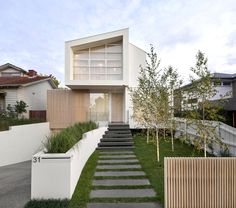 a modern house with stairs leading up to the front door and side yard area on either side