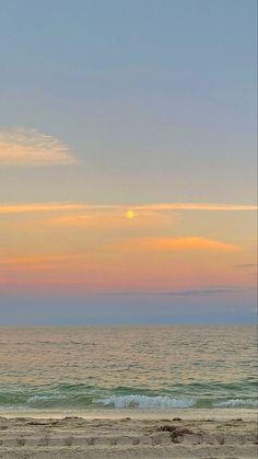 two people are walking on the beach with surfboards at sunset in the distance,