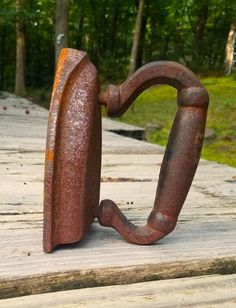 an old rusted iron hook sitting on top of a wooden deck