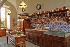 a kitchen filled with lots of copper colored pots and pans on the wall next to a sink