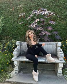 a woman sitting on top of a bench next to a tree