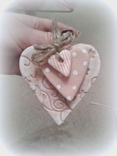 a hand holding a pink heart shaped ornament