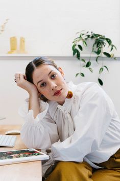 a woman sitting at a desk with her hand on her head and looking off to the side