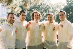 a group of young men standing next to each other in front of a pine tree