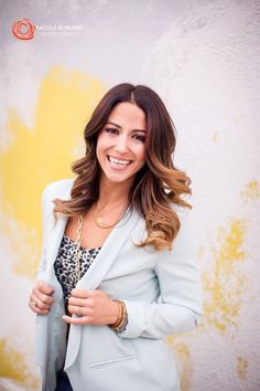 a smiling woman in a blue blazer and leopard print shirt is posing for the camera