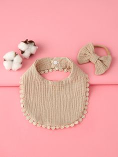 a baby bib, headband and cottons on a pink background