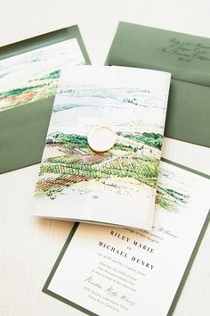 the wedding stationery is laid out on top of each other, including an envelope and ring