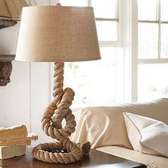 a rope lamp on a table next to a couch in a room with white walls