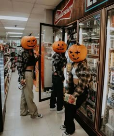 three people wearing pumpkin heads in a store