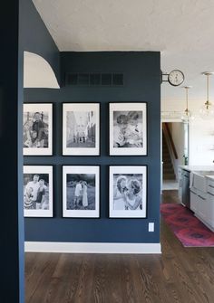 black and white photographs are hung on the wall in an open kitchen with wood flooring