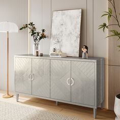 a gray cabinet with two doors and some plants on top of it in front of a white wall