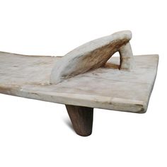 a wooden bench made out of driftwood with a curved foot rest on it's side