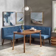 a corner table with two benches in front of it and paintings on the wall behind it