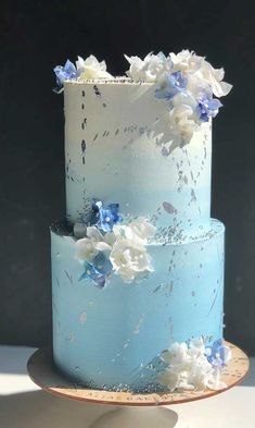 a three layer blue cake with white and blue flowers