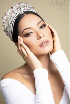 a woman wearing a tiara and holding her hand to her face while posing for the camera